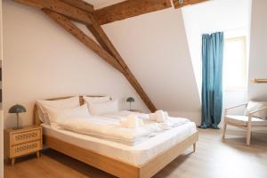 a bedroom with a large white bed and a chair at ღLiboria Villa Münter in Murnau am Staffelsee