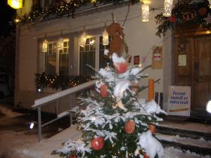 un árbol de Navidad cubierto de nieve frente a un edificio en Hotel de Commune, en Dombresson