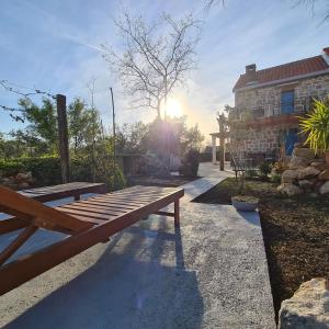 a wooden bench sitting in front of a house at Altes Steinhaus Goranova Kuca in Seline