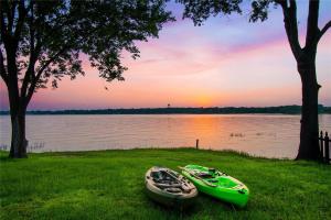 two canoes sitting on the grass next to a lake at Modern Lakeside Paradise - Waterfront 2 Patios home in Mabank