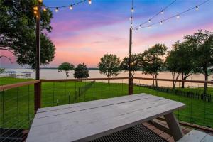 a wooden picnic table with a view of the water at Modern Lakeside Paradise - Waterfront 2 Patios home in Mabank +12 photos