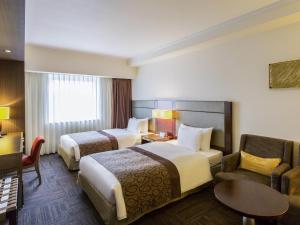 ein Hotelzimmer mit zwei Betten und einer Couch in der Unterkunft Ibis Styles Sapporo in Sapporo