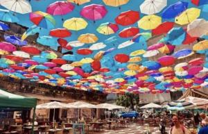a bunch of colorful umbrellas hanging in the air at House Lurokè in Catania