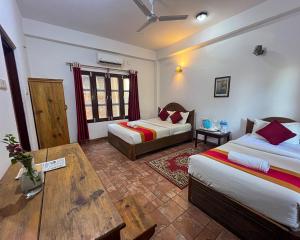 a hotel room with two beds and a table at Chitwan Park Village in Sauraha
