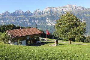 una casa en una colina con montañas al fondo en Fäsch, en Flumserberg