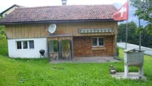 Una pequeña casa de ladrillo con una bandera en el patio. en Fäsch, en Flumserberg