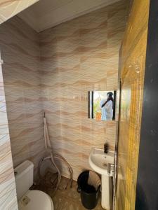 a man taking a picture of a bathroom with a toilet and sink at Exotic Modern 2BR Apartment in Independence Layout in Enugu +23 photos