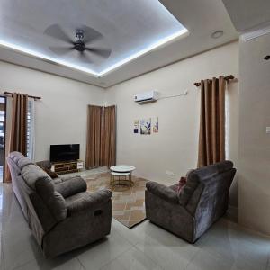 a living room with two couches and a ceiling fan at Residensi Lourve Homestay Sungai Petani in Sungai Petani