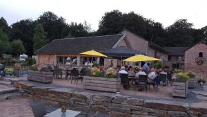 a group of people sitting at a restaurant with yellow umbrellas at Camping Natuurlijk Limburg - Appartement in Voeren