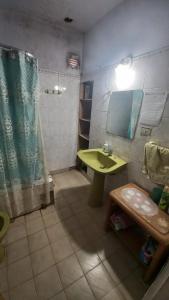 baño con lavabo verde y espejo en Hostel, La Casa del Patio, en Bahía Blanca