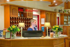 a woman speaking at a counter in a store at Montana Hotel Senden in Senden