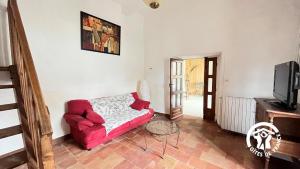 a living room with a red couch and a tv at Chateau st-auriol - le caviste in Saint-Pierre-des-Champs