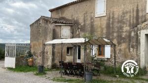 an old building with a table and chairs under an umbrella at Chateau st-auriol - le caviste in Saint-Pierre-des-Champs