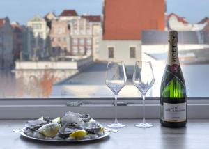 ポズナンにあるOysters & Bubbles Gastro Rooms Rynek Squareのワイン1本とワイングラス2杯(テーブル上)