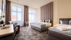 ポズナンにあるOysters & Bubbles Gastro Rooms Rynek Squareのベッド2台とソファがあるホテルの部屋