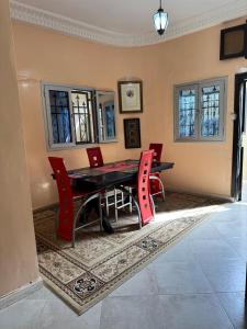 a dining room with a table and red chairs at Chez SIDIBE in Saint-Louis