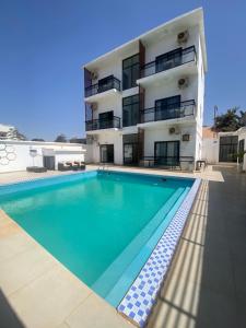 um prédio com piscina em frente a um prédio em chamis apartment em Bijilo mais 6 fotografias