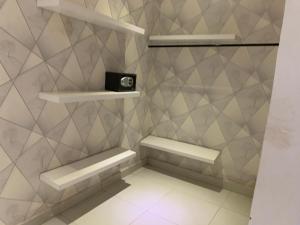 um banheiro com duas prateleiras e um relógio na parede em chamis apartment em Bijilo