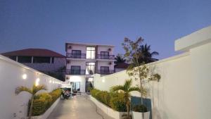 um prédio branco com palmeiras na frente em chamis apartment em Bijilo