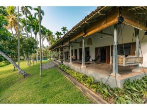 a house with a porch with palm trees in the background at Dutch house 5 bedrms pool chef in Habaraduwa Central
