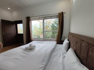 um quarto com uma grande cama branca e uma janela em Monal Homestay, Bhimtal em Bhīm Tāl