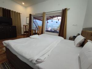 uma grande cama branca em um quarto com janela em Monal Homestay, Bhimtal em Bhīm Tāl