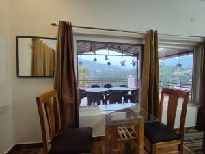 uma sala de jantar com mesa e cadeiras de vidro em Monal Homestay, Bhimtal em Bhīm Tāl