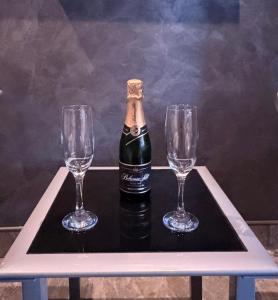 una botella de champán en una bandeja con dos copas de vino en wellnesshonezovice, en Honezovice