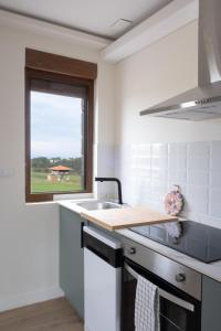 a white kitchen with a sink and a window at Salitre - El Silencio Apartamentos in Castañeras +10 photos