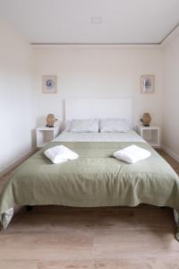a white bedroom with a large bed with two pillows at Salitre - El Silencio Apartamentos in Castañeras