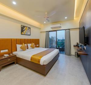 una habitación de hotel con una cama y un televisor en Hotel The Golden Oaks, Kolhapur, en Kolhapur