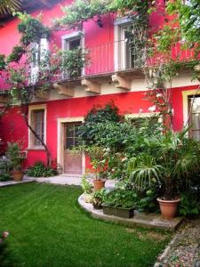 a red building with plants in a yard at Glicine in Miasino