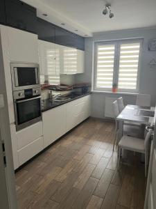 a kitchen with white cabinets and a table with a dining room at Apartament Zacisze in Kalisz +3 photos