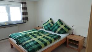 een slaapkamer met een bed met een groen en geel geblokte deken bij Fewo Am Skihang Og in Eibenstock