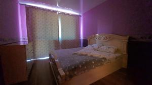 ein Schlafzimmer mit einem Bett in einem lila Zimmer in der Unterkunft 2-х комнатная квартира в центре in Qaraghandy