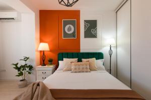 une chambre avec un lit avec un mur orange dans l'établissement Ivory Residence - Modern Minimalist Studio Apartment, à Bucarest 28 autres photos