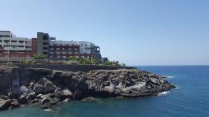 a rock formation in the ocean with buildings in the background at VV Paraíso Del Sur in Playa Paraiso