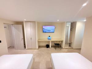 The Host at Santa Marta في سانتا مارتا: غرفة بسريرين ومكتب مع تلفزيون على الحائط +5 صور