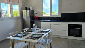 a kitchen with a table with chairs and a refrigerator at La Fleur Doré F3 Le Vauclin in Le Vauclin
