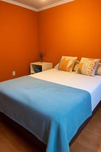 ein Schlafzimmer mit einem großen Bett mit einer orangefarbenen Wand in der Unterkunft Hospedagem Nova Terra in Alto Paraíso de Goiás