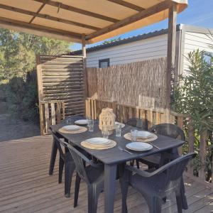 a black table and chairs on a wooden deck at EL Miya Sol Mobil Home à 200m de la Plage in Torreilles