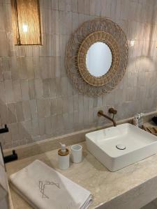 a bathroom with a white sink and a mirror at Riad A l'Ombre du Palais in Oulad Akkou +69 photos