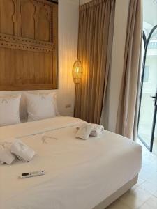 a bedroom with a large white bed with a thermometer on it at Riad A l'Ombre du Palais in Oulad Akkou