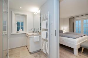 ein weißes Bad mit einem Bett und einem Waschbecken in der Unterkunft Haus Carstensen Nord in Keitum + 30 Fotos