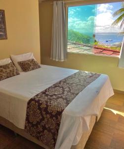 a bedroom with a bed with a large window at Pousada Rosa do Mar in Gamboa