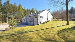 a white building on a grassy hill with a tree at Villa La Chauve Souris in Houffalize