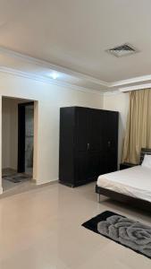 a bedroom with a bed and a black cabinet at Zayed chalet for families in Al Khīrān