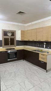 a large kitchen with wooden cabinets and a sink at Zayed chalet for families in Al Khīrān