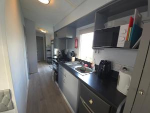 eine kleine Küche mit Spüle und Arbeitsplatte in der Unterkunft The Retreat at Marine Holiday Park in Rhyl
