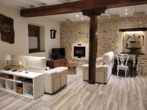 una sala de estar con muebles blancos y una pared de piedra. en Casa rural El Yunque, en Tarilonte